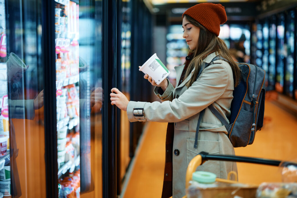 A young woman reads a dairy product nutrition label that provides processed food transparency to consumers.