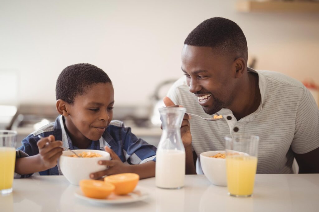 A father and son are shown eating cereal, a processed food that helps meet consumers’ dietary needs through food processing innovation.