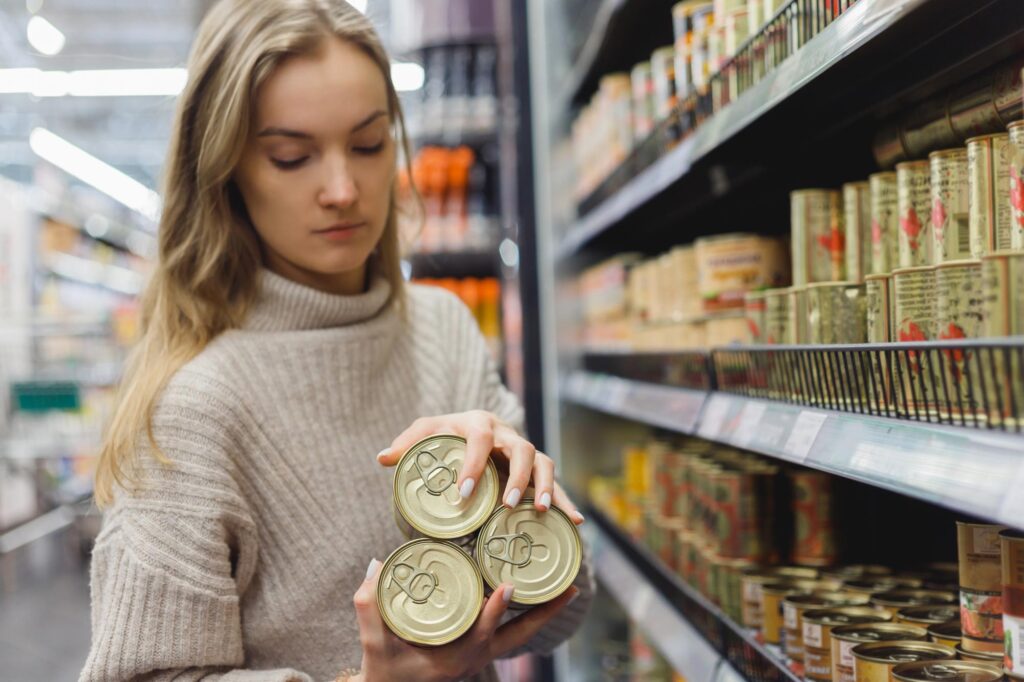 A woman holds shelf-stable cans of processed foods that play a role in improving food security and food supply.